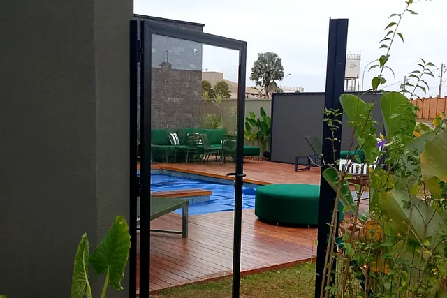 Porta de vidro temperado com estrutura de alumínio dando acesso à área de piscina.
