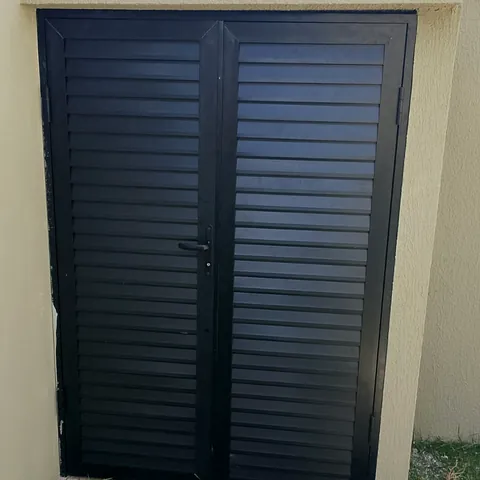 Portão de alumínio em lambril preto de duas folhas.